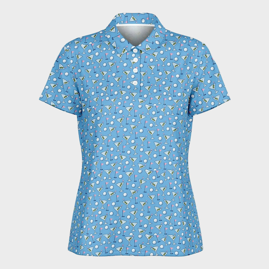 A women's short-sleeve polo shirt in light blue, featuring an allover pattern of golf balls, martini glasses, and cocktail umbrellas, displayed on a white mannequin torso against a solid white background.